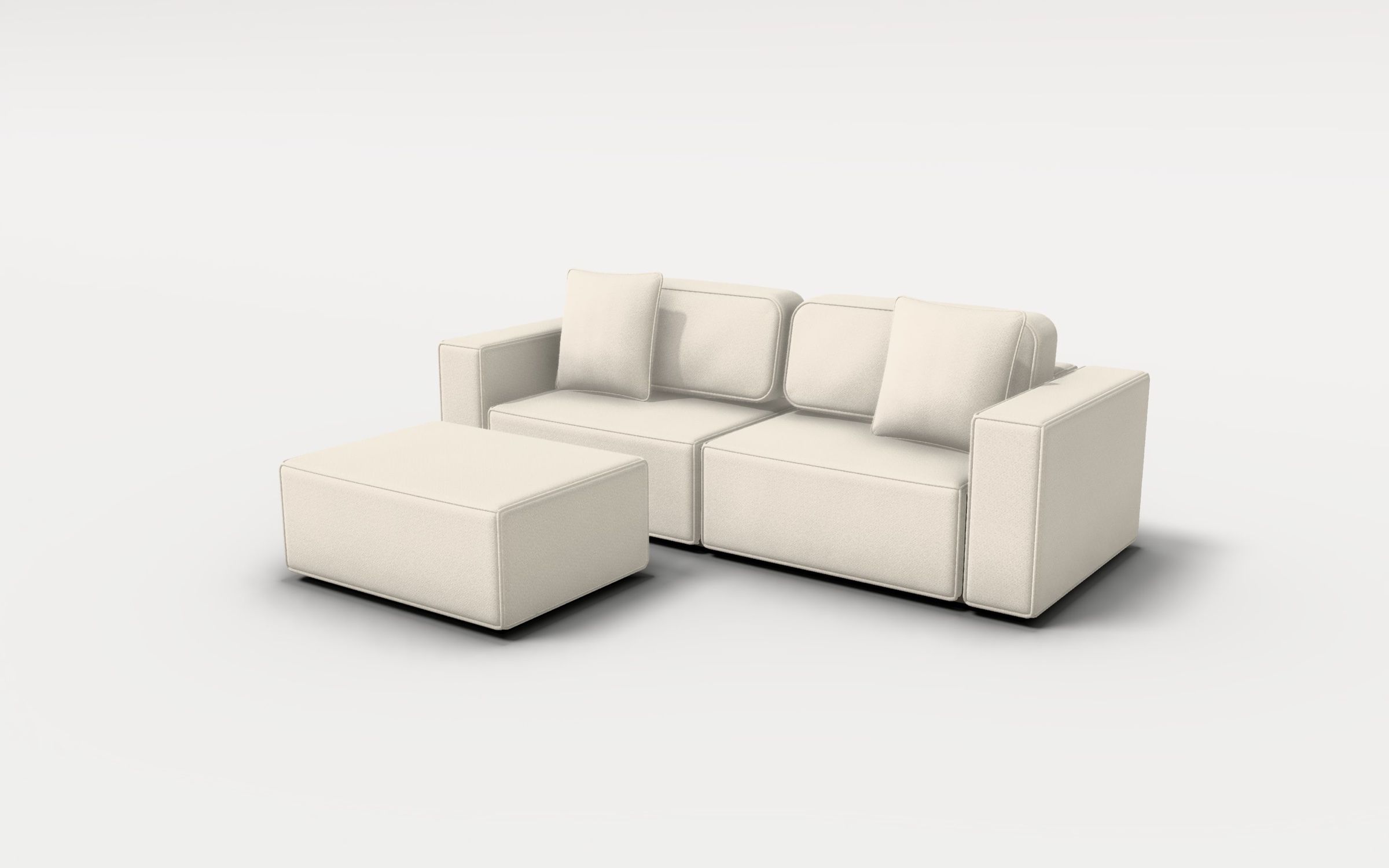 The two-seat sofa with its ottoman in a white photo studio, upholstered in a pale chenille, with two scatter cushions against the back cushions and a soft shadow on the floor.